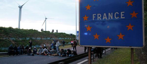 Migrants sit and block the road near a sign marked France in Coquelles, near Calais, France, July 30, 2015 Migrants sit and block the road near a sign marked France in Coquelles, near Calais, France, July 30, 2015 - Sputnik International