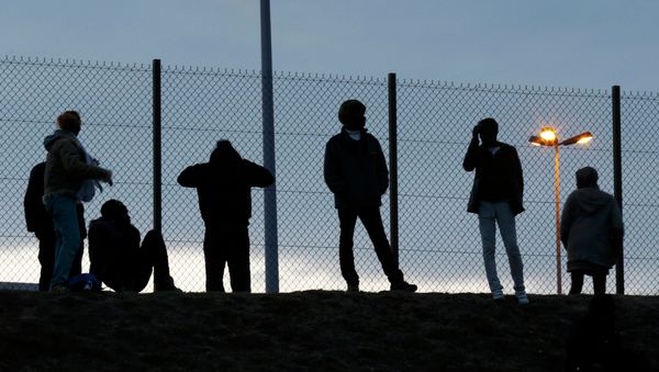 Migrants are seen in silhouette as they stand on a rise near a fence as they gather near the Channel Tunnel access in Frethun, near Calais, France, July 30, 2015 Migrants are seen in silhouette as they stand on a rise near a fence as they gather near the Channel Tunnel access in Frethun, near Calais, France, July 30, 2015 - Sputnik International