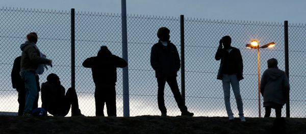 Migrants are seen in silhouette as they stand on a rise near a fence as they gather near the Channel Tunnel access in Frethun, near Calais, France, July 30, 2015 Migrants are seen in silhouette as they stand on a rise near a fence as they gather near the Channel Tunnel access in Frethun, near Calais, France, July 30, 2015 - Sputnik International