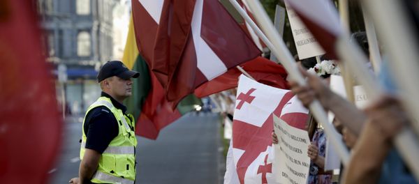 A police officer looks on as people attend a protest against European Union plans to host 250 refugees in Latvia over the next 2 years, in Riga, Latvia, August 4, 2015 A police officer looks on as people attend a protest against European Union plans to host 250 refugees in Latvia over the next 2 years, in Riga, Latvia, August 4, 2015 - Sputnik International