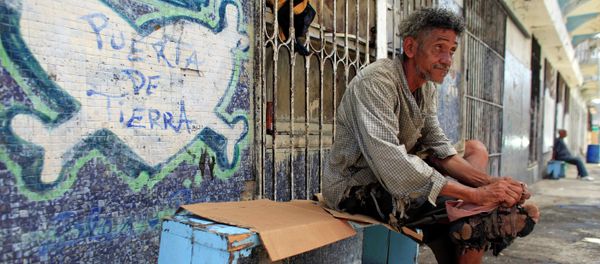 A homeless man improvises his shoes with pieces of cloth in front of a closed down business in Puerta de Tierra in the outskirts of Old San Juan, Puerto Rico, Sunday, Aug. 2, 2015 A homeless man improvises his shoes with pieces of cloth in front of a closed down business in Puerta de Tierra in the outskirts of Old San Juan, Puerto Rico, Sunday, Aug. 2, 2015 - Sputnik International