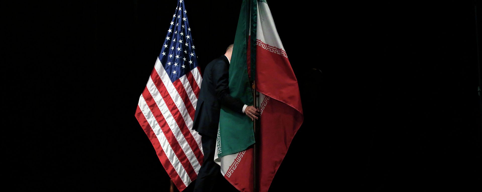 A staff member removes the Iranian flag from the stage after a group picture with foreign ministers and representatives of Unites States, Iran etc. - Sputnik International, 1920, 21.06.2026