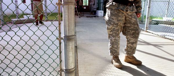 In this photo, reviewed by the US Military, a guard leans on a fencepost as a Guantanamo detainee, left, jogs inside the exercise yard at Camp 5 detention center, the U.S. Naval Base, in Guantanamo Bay, Cuba, January 21, 2009 - Sputnik International