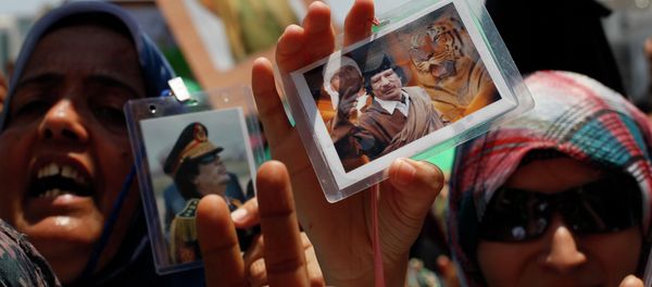 In this file photo taken on a government-organized tour Libyan women show their badges with portraits of Moammar Gadhafi and his son Seif al-Islam as they rally at the Green Square in downtown Tripoli, Libya, on Thursday, June 23, 2011 - Sputnik International