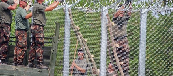 A picture is taken on July 18, 2015 shows soldiers of the Hungarian Army's technical unit finish the first completed elements of the 150 meter-long metal fence at the Hungarian-Serbian border nearby Morahalom village. - Sputnik International