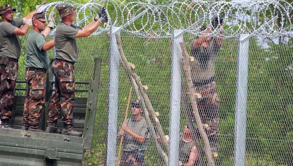 A picture is taken on July 18, 2015 shows soldiers of the Hungarian Army's technical unit finish the first completed elements of the 150 meter-long metal fence at the Hungarian-Serbian border nearby Morahalom village. A picture is taken on July 18, 2015 shows soldiers of the Hungarian Army's technical unit finish the first completed elements of the 150 meter-long metal fence at the Hungarian-Serbian border nearby Morahalom village. - Sputnik International