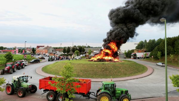 Tractors are parked around a roundabout with a fire burning in the middle during demonstration by dairy farmers on July 29, 2015 in Ghislenghien - Sputnik International
