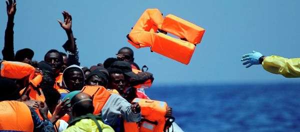 A Belgian nav.y sailor passes life vests to migrants sitting in a rubber boat as they approach the Belgian Navy Vessel Godetia during a search and rescue mission in the Mediterranean Eea off the Libyan coasts, Tuesday, June 23, 2015 - Sputnik International