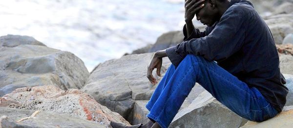 A migrant sits on rocks by the sea in Ventimiglia, at the Italian-French border, Tuesday, June 16, 2015. - Sputnik International