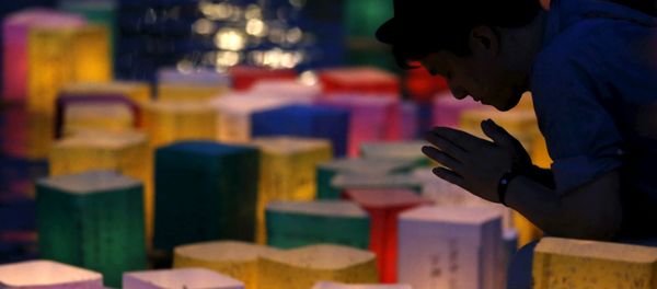 A man prays after releasing a paper lantern on the Motoyasu river facing the Atomic Bomb Dome in remembrance of atomic bomb victims on the 70th anniversary of the bombing of Hiroshima, western Japan, August 6, 2015. - Sputnik International