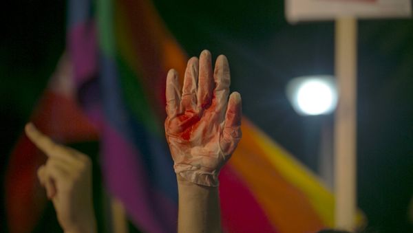 A protester holds up a glove covered in red during a protest against the violence towards the gay community in Tel Avi - Sputnik International