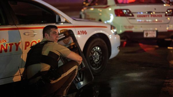 A St. Louis County police officer takes cover behind a car after shots were fired during a protest march on August 9, 2015 on West Florissant Avenue in Ferguson, Missouri - Sputnik International