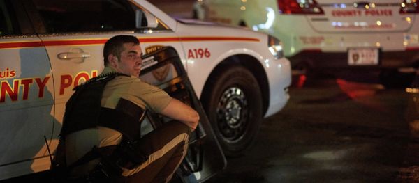 A St. Louis County police officer takes cover behind a car after shots were fired during a protest march on August 9, 2015 on West Florissant Avenue in Ferguson, Missouri - Sputnik International