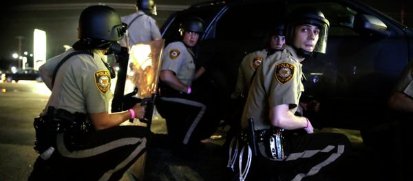 Police take cover behind a vehicle during a protest in Ferguson, Mo., Sunday, Aug. 9, 2015 - Sputnik International