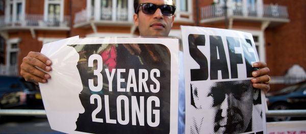 A supporter of Wikileaks founder Julian Assange holds banners outside the Ecuadorian embassy in London as he marks three years since Assange claimed asylum in the embassy on June 19, 2015. - Sputnik International