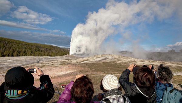Tourists photograph Old Faithful erupting at Yellowstone National Park in Montana. - Sputnik International