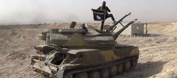 In this picture released on Wednesday, Aug. 5, 2015 by the Rased News Network a Facebook page affiliated with Islamic State militants, an Islamic State militant holds the group's flag as he stands on a tank they captured from Syrian government forces, in the town of Qaryatain southwest of Palmyra, central Syri - Sputnik International