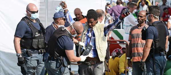 A police officer uses and hand held metal detector to check a man as he disembark from the patrol vessel Fiorillo of the Italian Coast Guard after it arrived in the port of Pozzallo on August 7, 2015 after saving some 387 migrants in the Sicilian Channel - Sputnik International