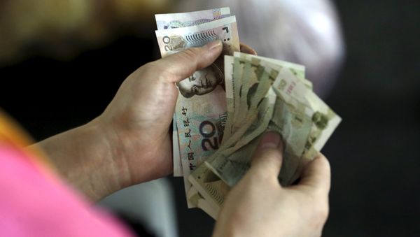 A customer counts Chinese Yuan notes at a market in Beijing, August 12, 2015 - Sputnik International