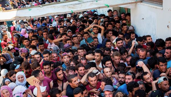 Syrian migrants and refugees gather at a makeshift migrant detention center at Kos' abandoned football stadium after crossing from Turkey, at the southeastern island of Kos, Greece, Wednesday, Aug. 12, 2015. - Sputnik International