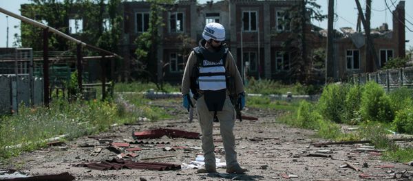 An OSCE monitor checks the territory for mines during a patrol in Shyrokyne, Donetsk region eastern Ukraine, Saturday, July 4, 2015 - Sputnik International