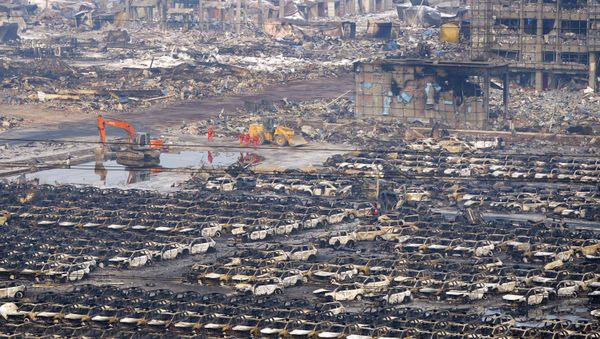 Rescuers walk next to damaged vehicles at the site of Wednesday night's explosions in Binhai new district of Tianjin, China, August 15, 2015 - Sputnik International