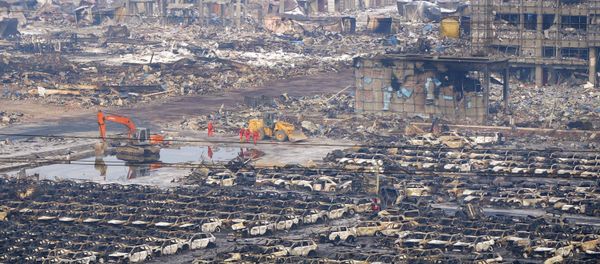 Rescuers walk next to damaged vehicles at the site of Wednesday night's explosions in Binhai new district of Tianjin, China, August 15, 2015 - Sputnik International