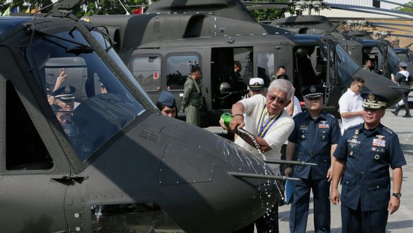 Philippine National Defense Chief Voltaire Gazmin pours champagne on a Bell-412EP helicopter. - Sputnik International