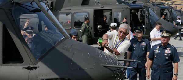 Philippine National Defense Chief Voltaire Gazmin pours champagne on a Bell-412EP helicopter. - Sputnik International