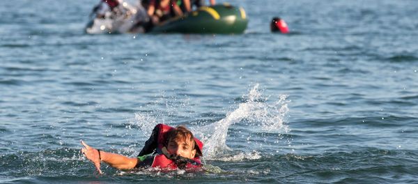 Migrants and refugees, one of them swims, arrive after crossing from Turkey, at the southeastern island of Kos, Greece, Monday, Aug. 17, 2015 - Sputnik International