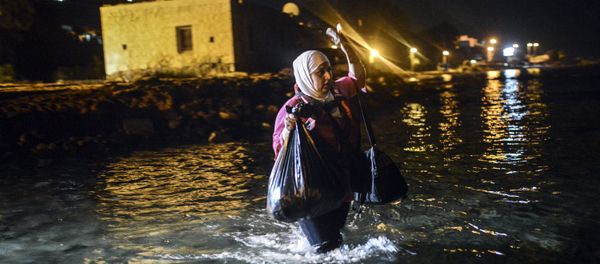 A migrant walks to a boat to reach the Greek island of Kos on early August 18, 2015. - Sputnik International