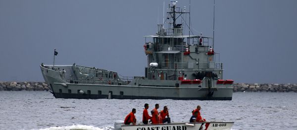 Members of the Philippine coast guard on a motorboat drive past one of the two decommissioned Landing Craft Heavy (LCH) vessels donated by the Australian government to the Philippines, docked at a bay in Manila August 9, 2015 - Sputnik International