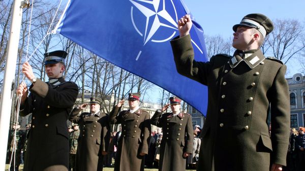 Latvian officers stand guard during the NATO flag rising ceremony in front of the Presidents castle in Riga - Sputnik International