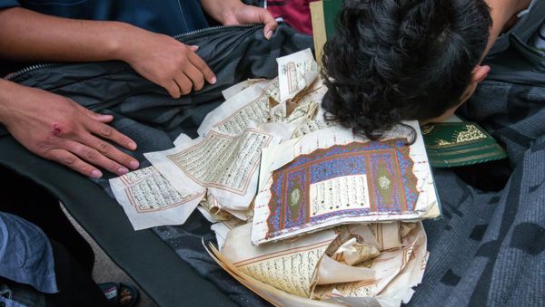 Refugees bow over ripped out pages from a Koran in a first registration center for refugees in Suhl, eastern Germany, on August 20, 2015 Refugees bow over ripped out pages from a Koran in a first registration center for refugees in Suhl, eastern Germany, on August 20, 2015 - Sputnik International