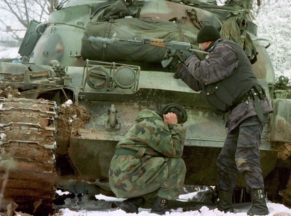 A Yugoslav special forces policeman shoots his rifle at opposing Kosovo Liberation Army forces as a Yugoslav Army tank driver covers his ears after coming under fire Tuesday Feb. 23, 1999 in the village of Bukos A Yugoslav special forces policeman shoots his rifle at opposing Kosovo Liberation Army forces as a Yugoslav Army tank driver covers his ears after coming under fire Tuesday Feb. 23, 1999 in the village of Bukos - Sputnik International