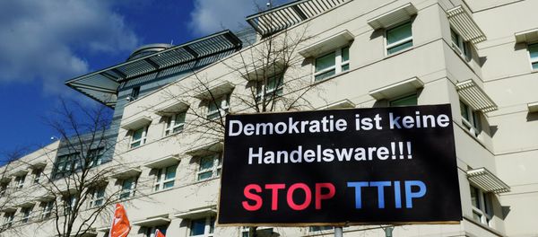 A sign reading Democracy is no trading good, Stop TTIP is lifted in front of the US embassy during a protest against the proposed US-EU free trade pact or Transatlantic Trade and Investment Partnership (TTIP) in Berlin on April 18, 2015 - Sputnik International