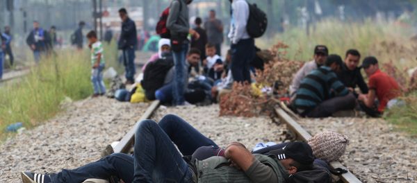 Migrants rest while waiting to pass the Greek-Macedonian border, guarded by Macedonian police near the town of Idomeni, northern Greece, on August 21, 2015 - Sputnik International