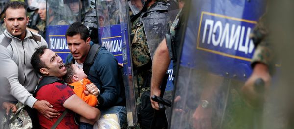 Migrant men help a fellow migrant man holding a boy as they are stuck between Macedonian riot police officers and migrants during a clash near the border train station of Idomeni, northern Greece, as they wait to be allowed by the Macedonian police to cross the border from Greece to Macedonia, Friday, Aug. 21, 2015 Migrant men help a fellow migrant man holding a boy as they are stuck between Macedonian riot police officers and migrants during a clash near the border train station of Idomeni, northern Greece, as they wait to be allowed by the Macedonian police to cross the border from Greece to Macedonia, Friday, Aug. 21, 2015 - Sputnik International