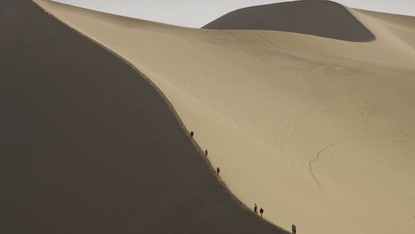 Tourists ride camels on the edge of the desert that threatens to engulf the ancient Chinese city of Dunhuang in China's northwest Gansu province. (File) Tourists ride camels on the edge of the desert that threatens to engulf the ancient Chinese city of Dunhuang in China's northwest Gansu province. (File) - Sputnik International