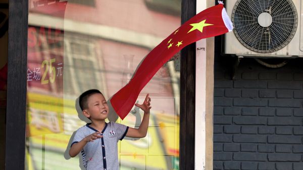 A child plays with a Chinese national flag near an area cordoned off for rehearsals ahead of a military parade to commemorate the end of World War II in Beijing, Saturday, Aug. 22, 2015 - Sputnik International