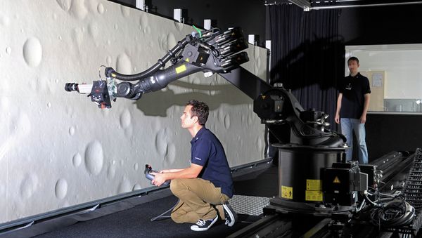 Marco Sagliano (L) and Michael Conradt (R), research assistants at the German Centre for Aerospace (DLR) guide a robotic-optical navigation device for landing on the moon at a test stand in Bremen Marco Sagliano (L) and Michael Conradt (R), research assistants at the German Centre for Aerospace (DLR) guide a robotic-optical navigation device for landing on the moon at a test stand in Bremen - Sputnik International