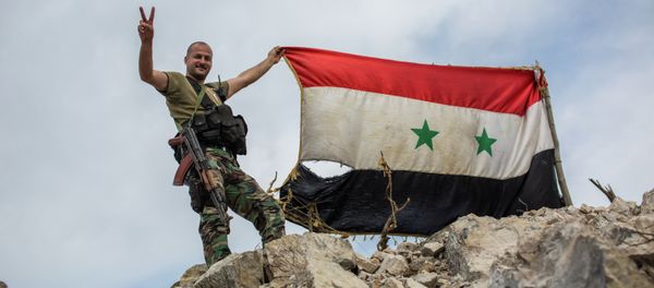 A government soldier with the Syrian flag on a location on top of a hill not far from Kessab on the Turkish border following an Islamist takeover of the town A government soldier with the Syrian flag on a location on top of a hill not far from Kessab on the Turkish border following an Islamist takeover of the town - Sputnik International