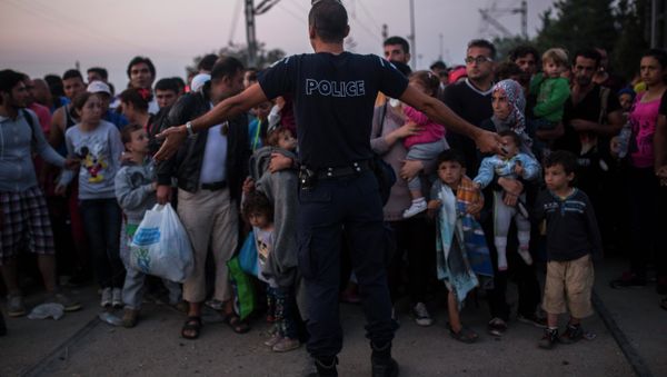 A Greek police officer gives orders to Syrian refugees as they wait to cross the border from Greece to Macedonia, in the border town of Idomeni , northern Greece, on Wednesday, Aug. 26, 2015 A Greek police officer gives orders to Syrian refugees as they wait to cross the border from Greece to Macedonia, in the border town of Idomeni , northern Greece, on Wednesday, Aug. 26, 2015 - Sputnik International