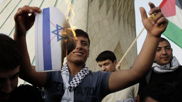 An Iranian demonstrator burns a representation of the Israeli flag with red lines indicating cancellation, in a pro-Palestinian demonstration in Tehran, Iran - Sputnik International