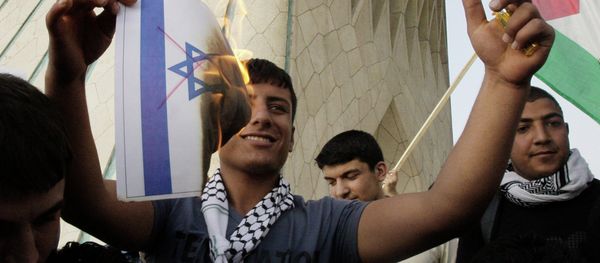 An Iranian demonstrator burns a representation of the Israeli flag with red lines indicating cancellation, in a pro-Palestinian demonstration in Tehran, Iran - Sputnik International
