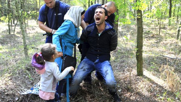 Hungarian policemen detain a Syrian migrant family after they entered Hungary at the border with Serbia, near Roszke, August 28, 2015. Hungarian policemen detain a Syrian migrant family after they entered Hungary at the border with Serbia, near Roszke, August 28, 2015. - Sputnik International