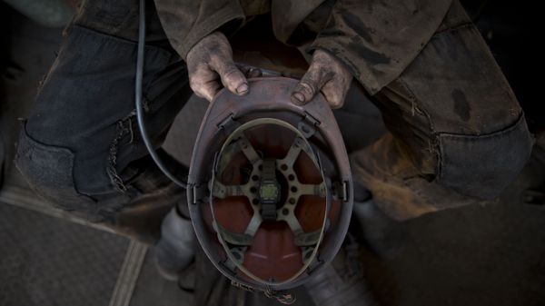 A Ukrainian coal miner holds his helmet after finishing his shift at a coal mine outside Donetsk, Ukraine - Sputnik International
