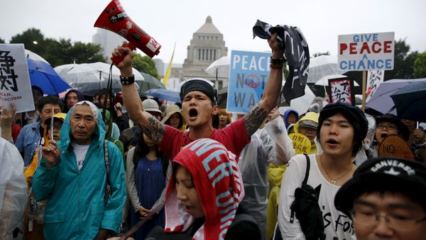 People hold placards and shout slogans as they protest against Japan's Prime Minister Shinzo Abe's security bill outside the parliament in Tokyo People hold placards and shout slogans as they protest against Japan's Prime Minister Shinzo Abe's security bill outside the parliament in Tokyo - Sputnik International