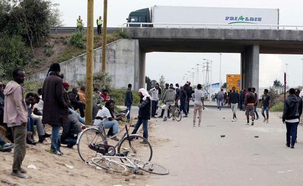 Migrants stand near a highway overpass near the makeshift camp called The New Jungle in Calais, France. - Sputnik International