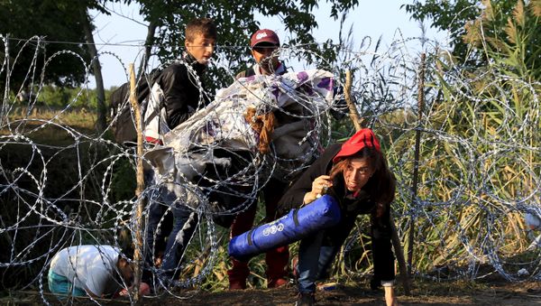 Syrian migrants cross under a fence as they enter Hungary at the border with Serbia, near Roszke, August 27, 2015 Syrian migrants cross under a fence as they enter Hungary at the border with Serbia, near Roszke, August 27, 2015 - Sputnik International